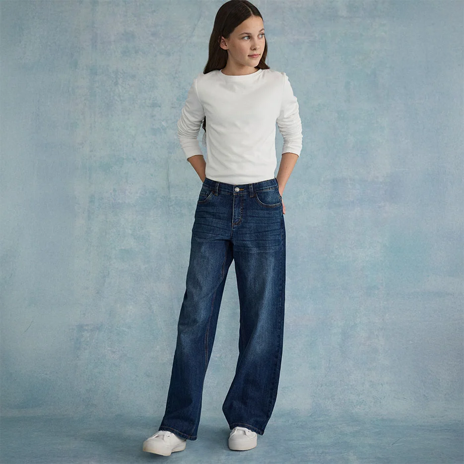 Biała, teksturowana góra połączona z szerokimi dżinsami i białymi sneakersami.