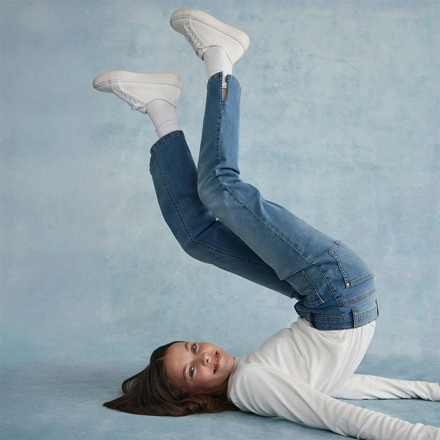 Biała bluzka w zestawieniu z jeansami skinny fit i białymi butami.