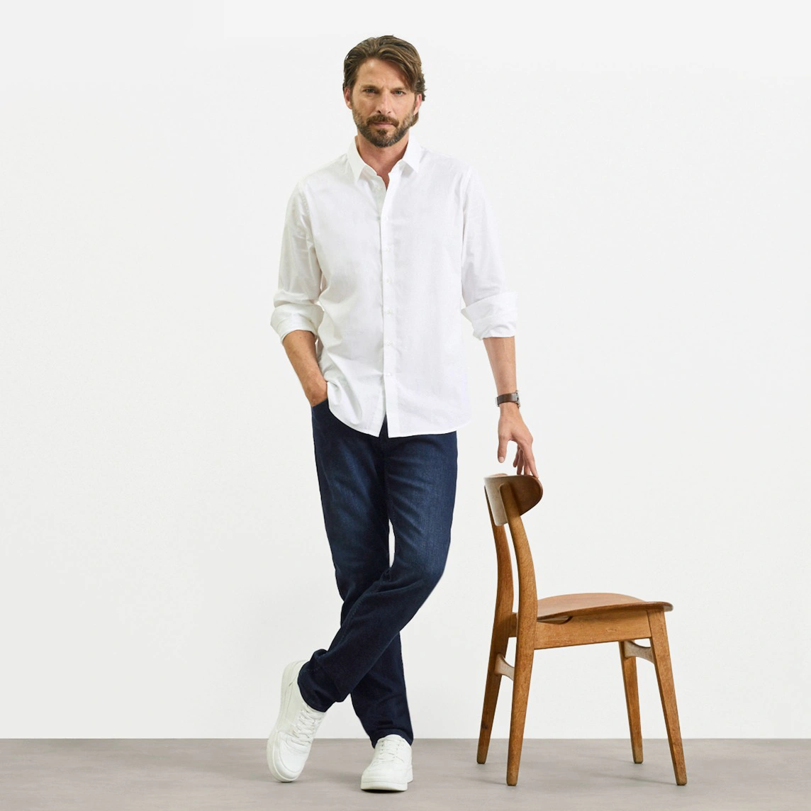 Biała koszula, ciemne jeansy o kroju Slim Fit i białe sneakersy.