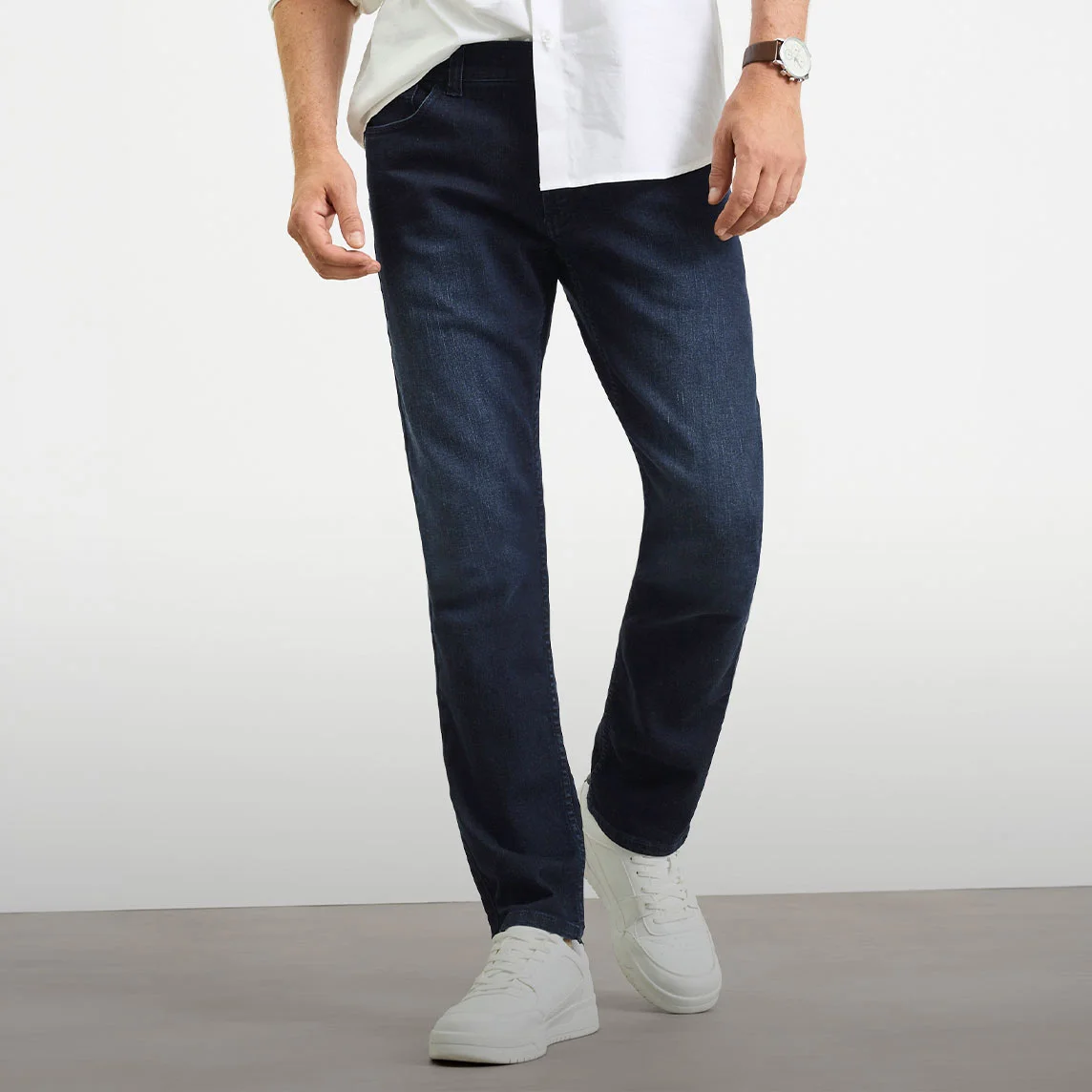 Biała koszula, ciemne jeansy o kroju Slim Fit i białe sneakersy.