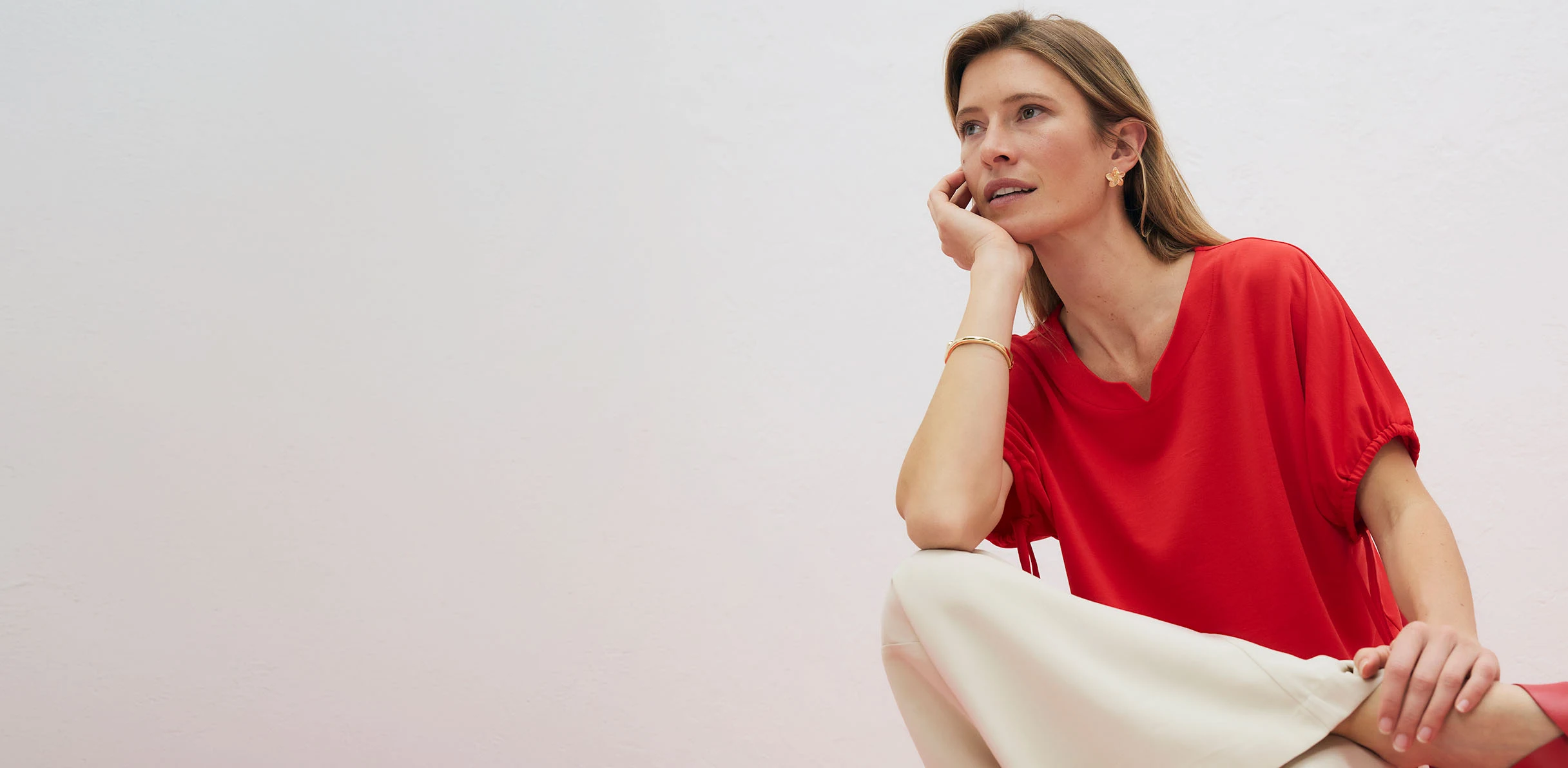 Szykowna, czerwona bluzka z subtelnym dekoltem w serek, doskonale komponująca się z jasnymi spodniami.