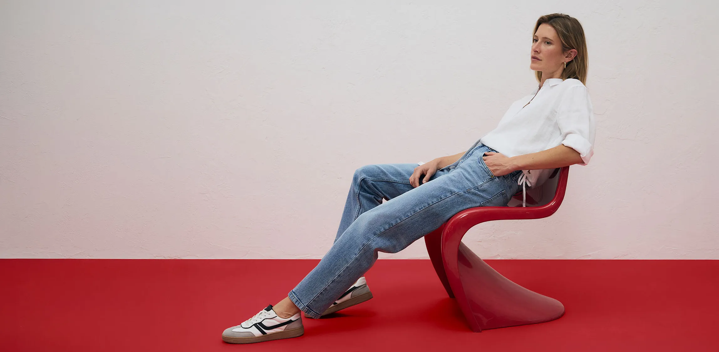 Biała koszula i jasnoniebieskie jeansy w połączeniu ze sneakersami.