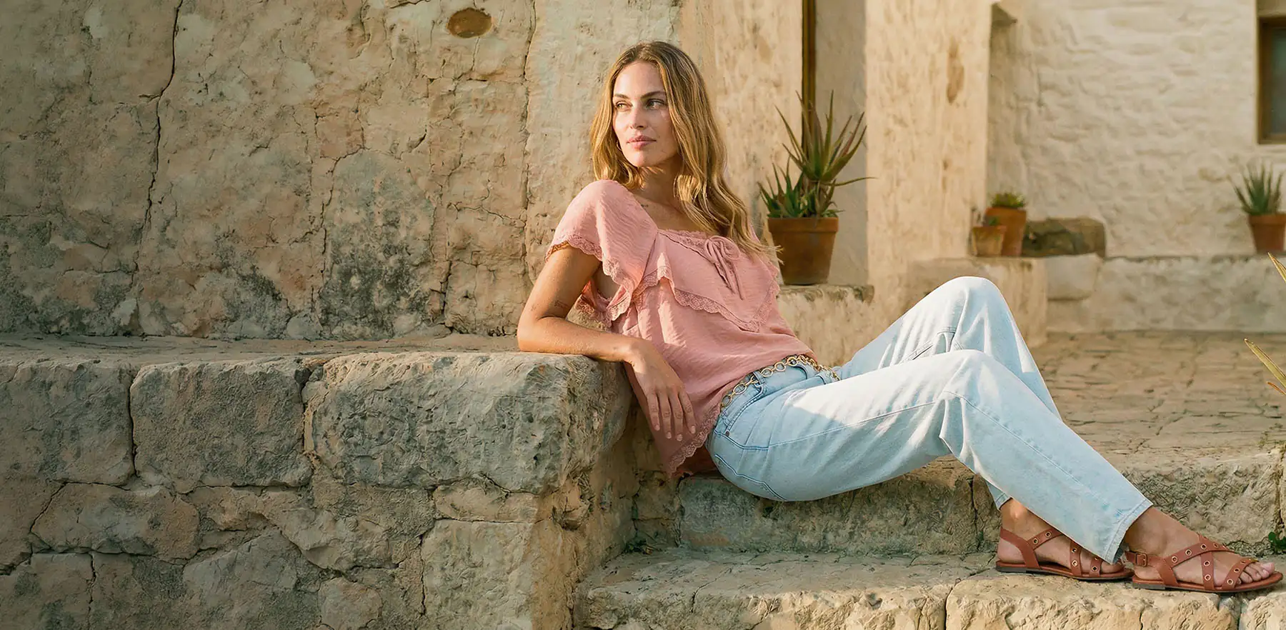 Jasnoróżowa bluzka z falbankami i jasnoniebieskie jeansy.