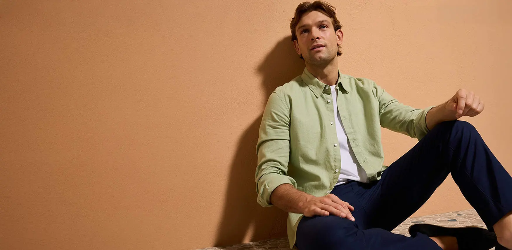 Koszula w pastelowej zieleni, granatowe spodnie i casualowe buty.