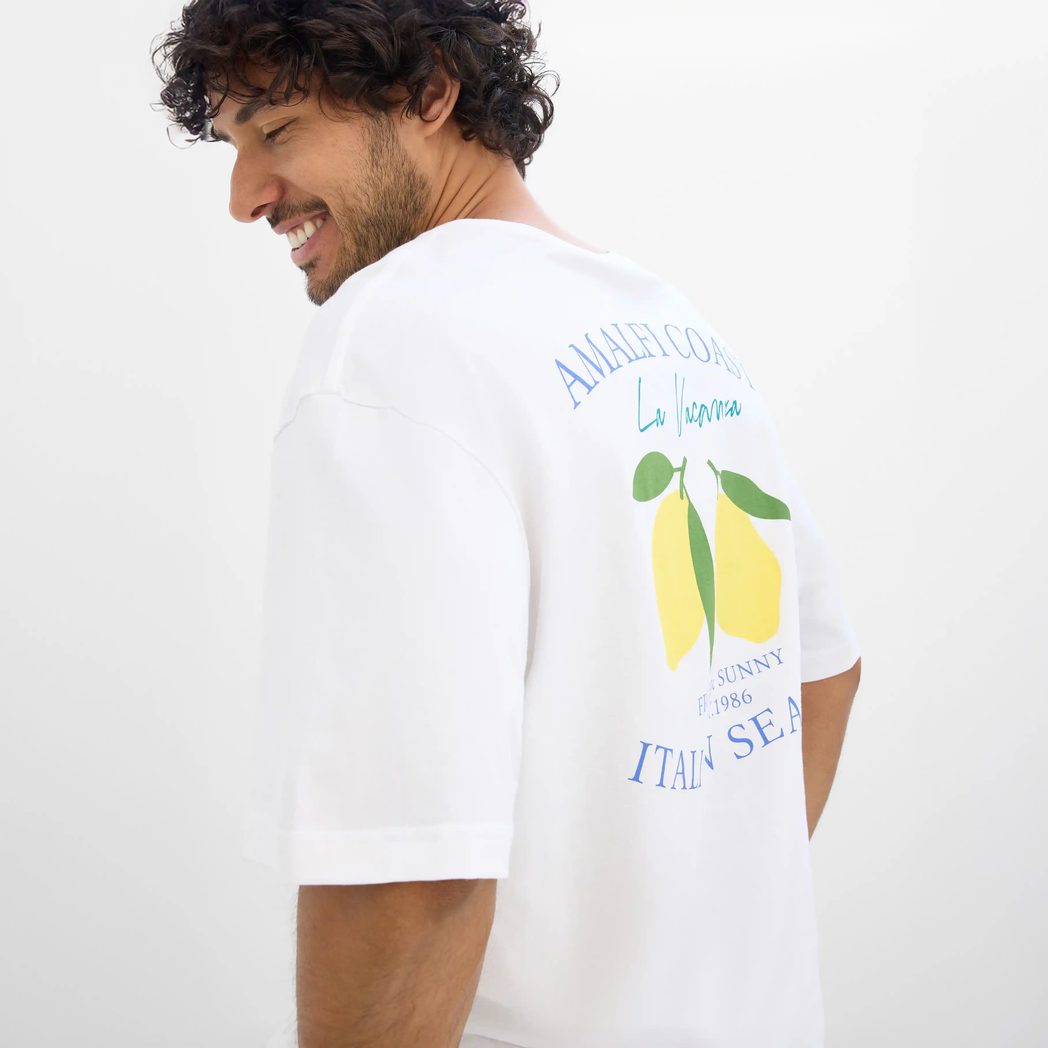 Biały T-shirt z motywem cytryn i napisem na plecach.